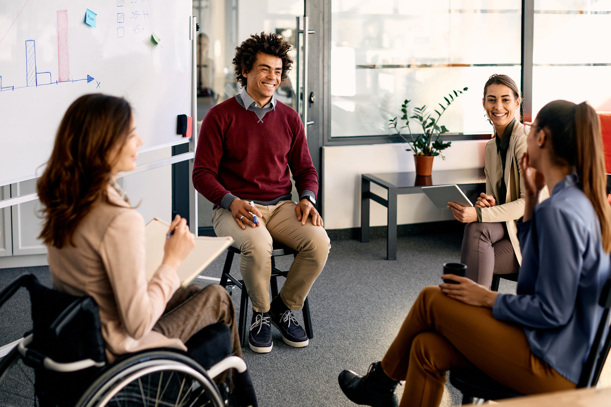 People in a circle in a meeting one with wheelchair and one leading group
